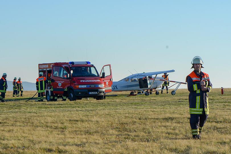 Feuerwehrleute stehen nach dem Flugunfall neben einem Sportflugzeug.