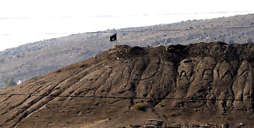 Die Flagge der Terrormiliz IS weht auf einem Hügel nahe der syrischen Stadt Kobane.