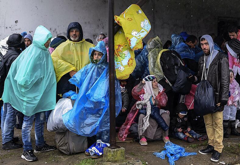 Flüchtlinge versuchen sich vor dem Regen zu schützen.