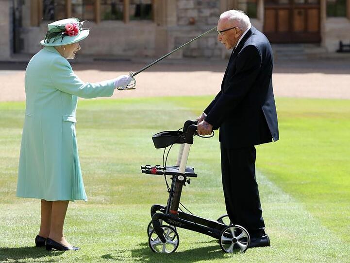 Königin Elizabeth II. (l) schlägt Tom Moore während einer Zeremonie im Freien auf Schloss Windsor zum Ritter.