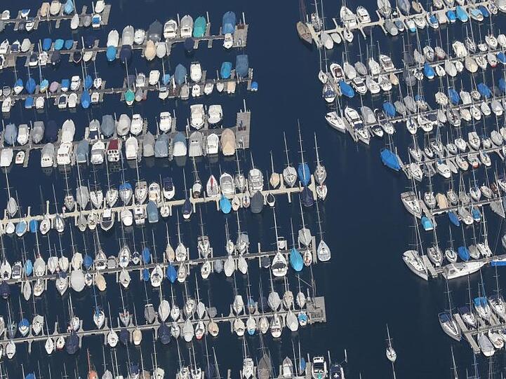 Boote liegen im Jachthafen von Langenargen am Bodensee im Sonnenschein. Foto: Thomas Warnack/Archivbild