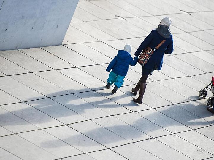 Eine Familie geht einen Weg entlang und wirft dabei lange Schatten. Foto: Lukas Schulze/dpa