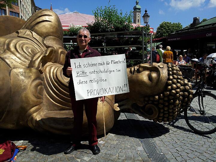 Der gefallene Buddha. "Bitte entschuldigen Sie diese religiöse Provokation", steht auf dem Schild.
