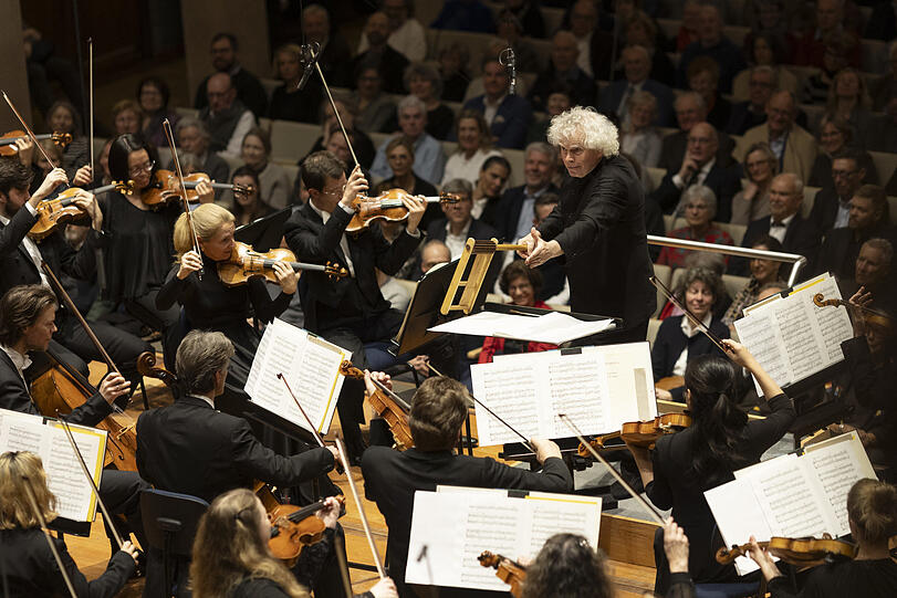 Simon Rattle mit Ratsche in den Schlusstakten der Uraufführung von Thomas Adès'"Aquifer" im Herkulessaal.