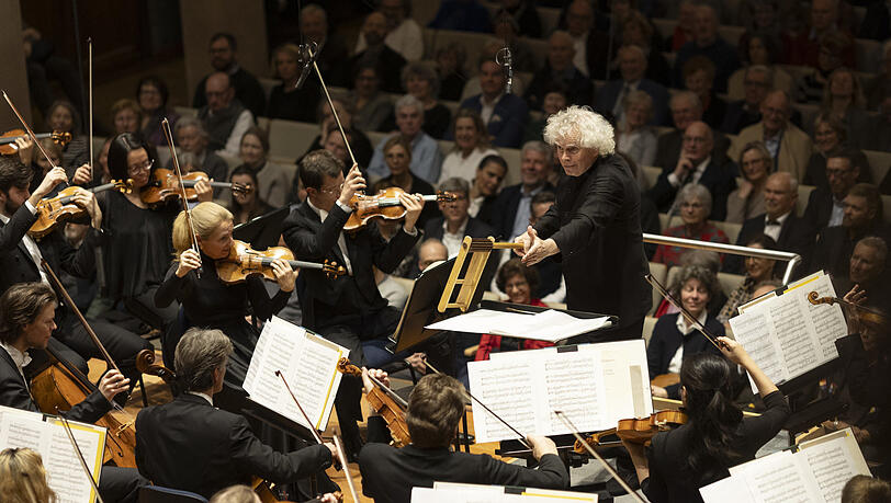 Simon Rattle mit Ratsche in den Schlusstakten der Uraufführung von Thomas Adès'"Aquifer" im Herkulessaal. Simon Rattle mit Ratsche in den Schlusstakten der Uraufführung von Thomas Adès'"Aquifer" im Herkulessaal.