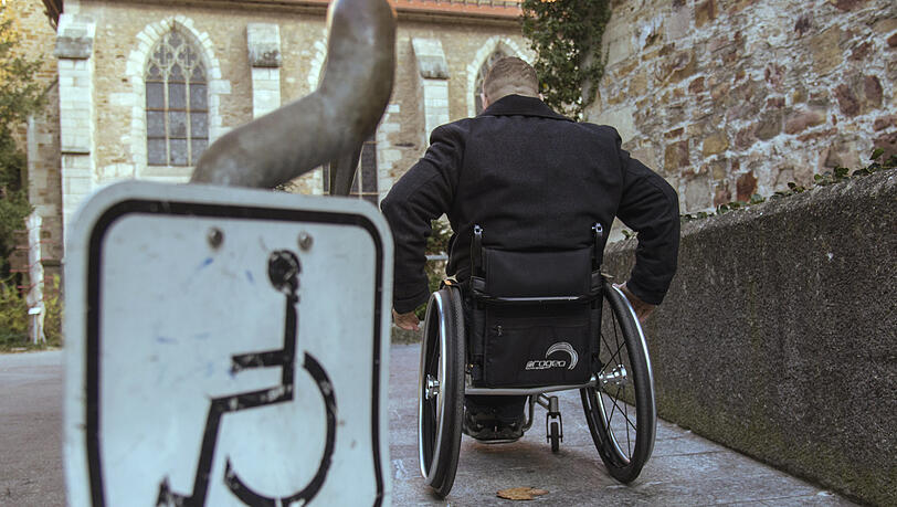 Ein Rollstuhlfahrer (Symbolbild). Der Bezirk Oberbayern wird für seinen Umgang mit Menschen mit Behinderung kritisiert.