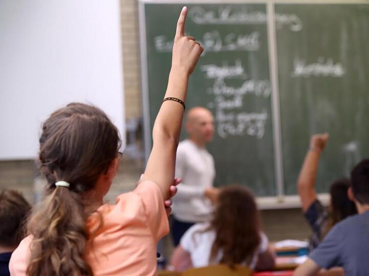 Eine Schülerin der fünften Klasse hebt im Unterricht den Finger. Foto: Daniel Karmann/dpa/Archivbild