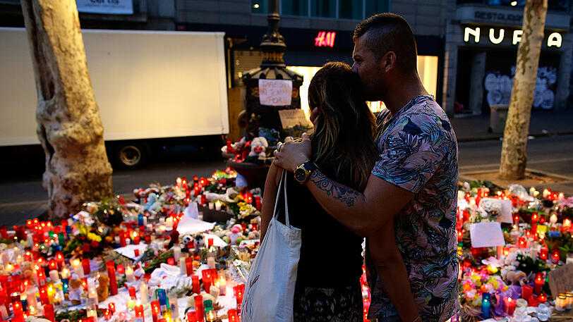 Menschen stehen am 19. August vor niedergelegten Kerzen und Blumen auf der Flaniermeile Las Ramblas in Barcelona. Zwei Tage zuvor kam es zur Terrorattacke.
