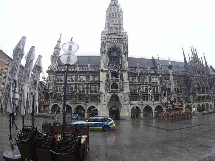 Vor dem Müncher Rathaus fährt ein Polizeiauto über den leeren Marienplatz.