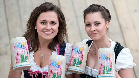 Im Bräurosl-Zelt präsentieren Laura (l) und Maja den Wiesn-Maßkrug 2016.