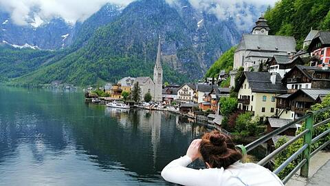 Eine Touristin fotografiert den Hallstätter See in Österreich. Hier scheint die Welt selbst im Corona-Sommer in der üblichen Ordnung zu sein.