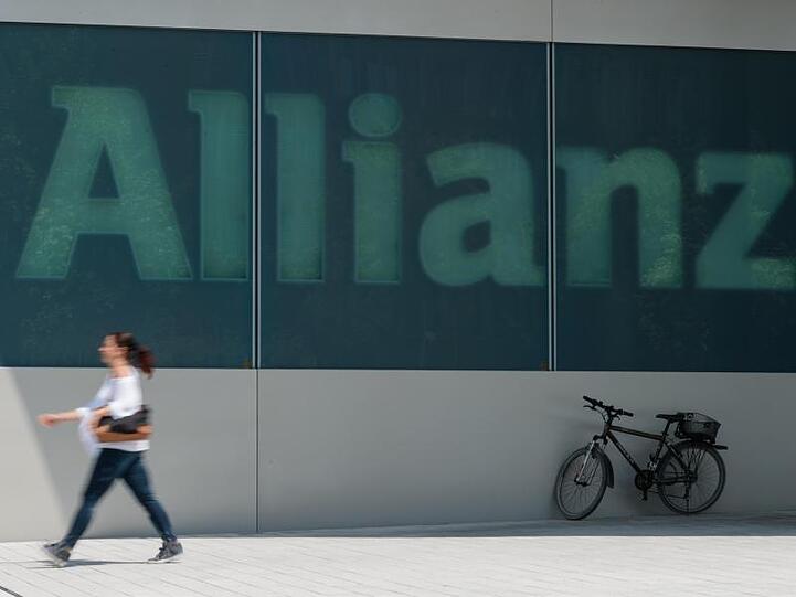 Eine Frau geht am an dem Schriftzug "Allianz" an einem Gebäude des Versicherungskonzerns vorbei. Foto: Andreas Gebert/dpa/Archivbild