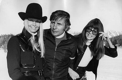 Model Mirja Larsson (l.), Gunter Sachs und ein weiteres Modell gehen durch den Schnee.