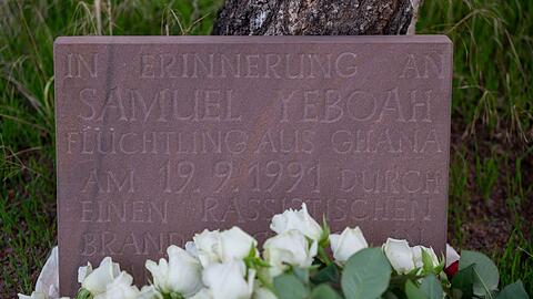 Teilnehmer der Gedenkkundgebung für den 1991 bei einem Brandanschlag getöteten ghanaischen Asylbewerber Samuel Yeboah haben an einem Gedenkstein Blumen abgelegt.