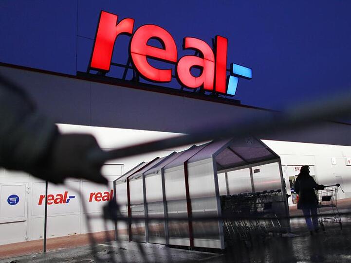 Ein Mann schiebt seinen Einkaufswagen vor einem Real Supermarkt. Foto: Oliver Berg/dpa/Archivbild