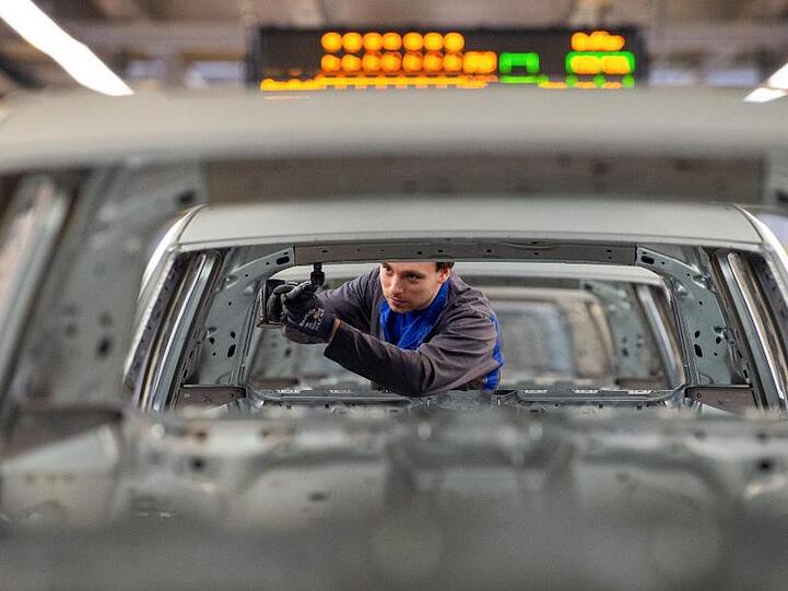 Ein Mitarbeiter schraubt im Karosseriebau im Werk in Wolfsburg an einem Volkswagen.