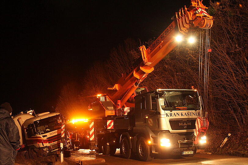 Ein Bergungsfahrzeug und zwei Kräne werden benötigt um den vollbeladenen LKW wieder auf die Straße zu ziehen.