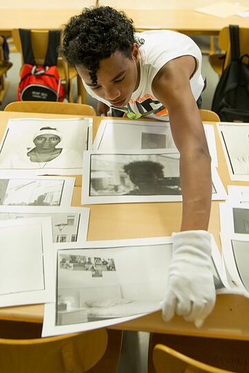 Der jugendliche Flüchtling Samson sortiert während der Vorbereitungen zur Ausstellung "Stories of my Life" im Museum im Kulturspeicher in Würzburg seine Fotos.