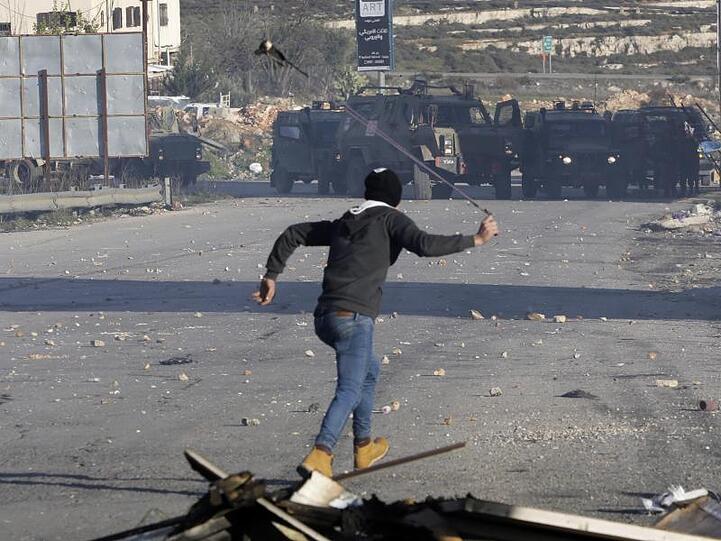 Ein Palästinenser wirft Steine auf israelische Sicherheitskräfte. Die israelische Armee hat die Stadt Ramallah, das Verwaltungszentrum der Palästinenser im Westjordanland, abgeriegelt.