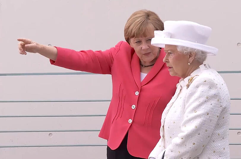 Bundeskanzlerin Angela Merkel zeigt der Queen auf der Terasse des Kanzleramtes, wo früher die Mauer gestanden hat.