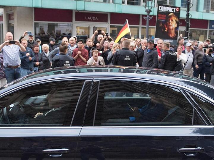 Der Dienstwagen der Bundeskanzlerin fährt an Demonstranten vor dem Albertinum vorbei.