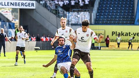 Rostocks Damian Roßbach (M) versucht St. Paulis Igor Matanovic vom Ball zu trennen.