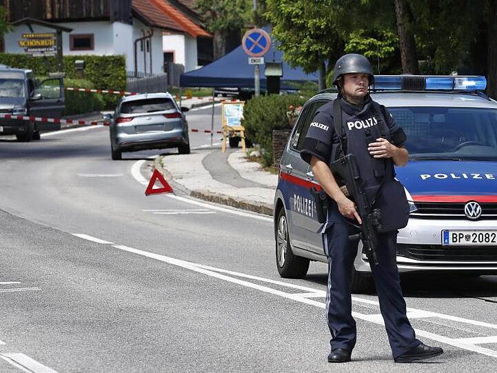 Ein bewaffneter Polizist sichert einen Straßenabschnitt am Tatort einer Tötung in der Gemeinde Villach.