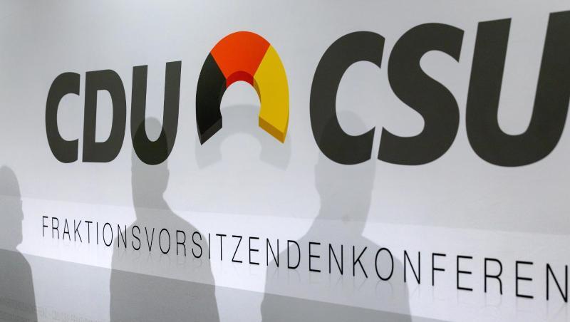 Schatten von Teilnehmern sind auf einer Werbewand der CDU/CSU zu sehen.