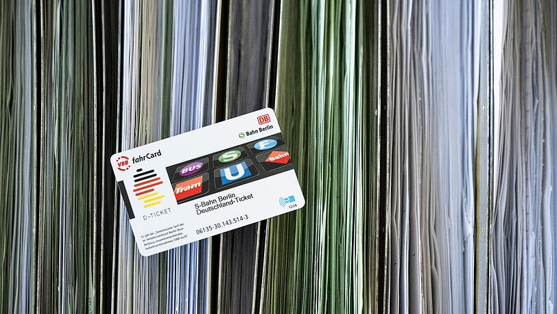 Eine Deutschland-Ticket-Chipkarte liegt auf sortierten Abo-Anträgen.