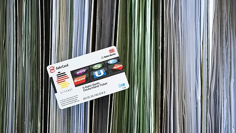 Eine Deutschland-Ticket-Chipkarte liegt auf sortierten Abo-Anträgen.