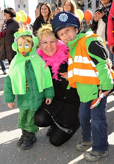 Der Froschkönig und ein kleiner Polizist mit ihrer Mutter beim Faschingstreiben am Rosenmontag in der Fußgängerzone