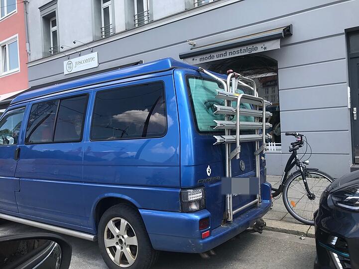 Ein VW-Bus mit Fahrradständer vor Läden in der Belgradstraße.