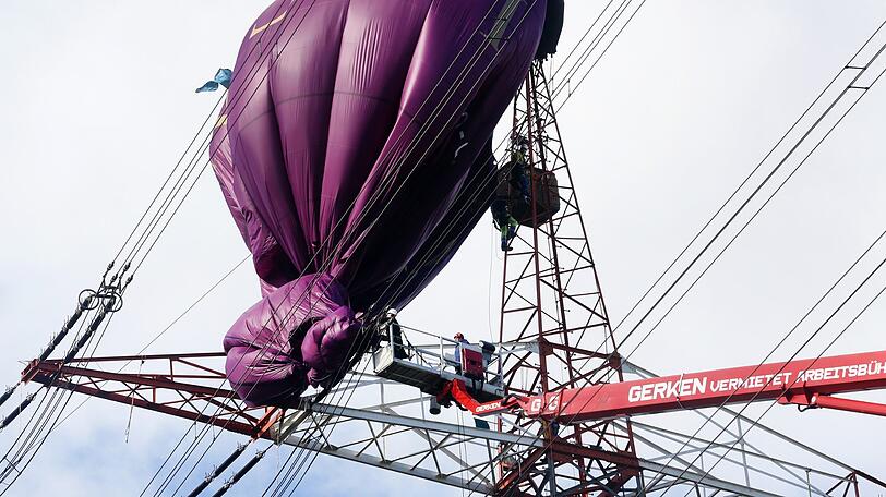 Der an einer Hochspannungsleitung verunglückte Heißluftballon wird von Höhenrettern und einem Hubsteiger geborgen.
