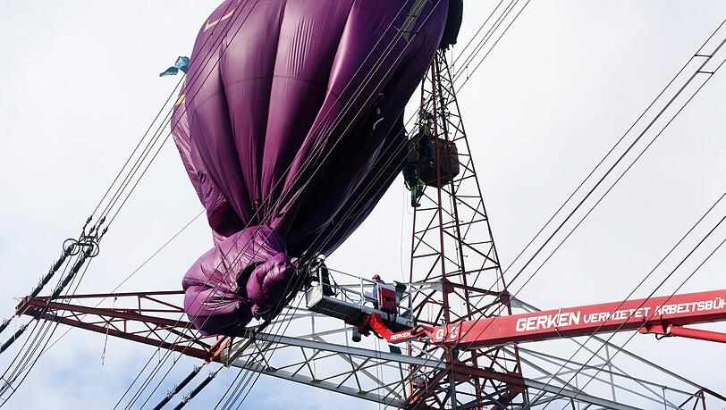 Der an einer Hochspannungsleitung verunglückte Heißluftballon wird von Höhenrettern und einem Hubsteiger geborgen. Der an einer Hochspannungsleitung verunglückte Heißluftballon wird von Höhenrettern und einem Hubsteiger geborgen.