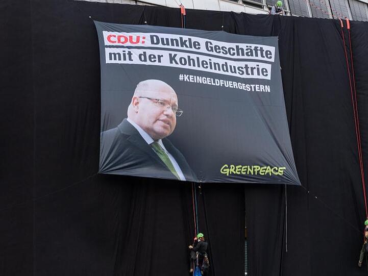 Die Aktivisten haben an der Fassade ein Transparent mit dem Konterfei von Wirtschaftsminister Peter Altmaier und dem Schriftzug "CDU: Dunkle Geschäfte mit der Kohleindustrie" angebracht.
