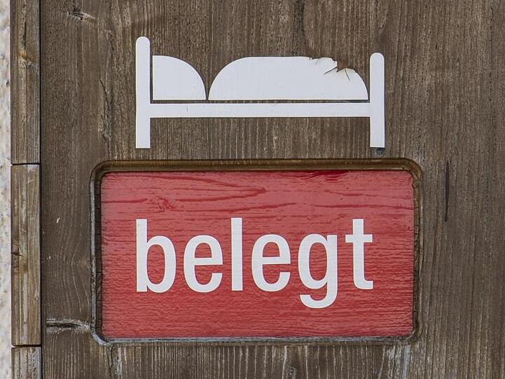 Eine Holztafel an einer Ferienwohnung zeigt an, dass die Zimmer belegt sind. Foto: Patrick Seeger/dpa/Symbolbild