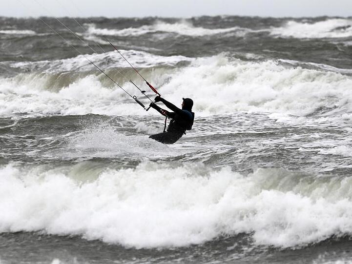 Ein Kite-Surfer nutzt den stürmischen Wind über der aufgewühlten Ostsee in Warnemünde.