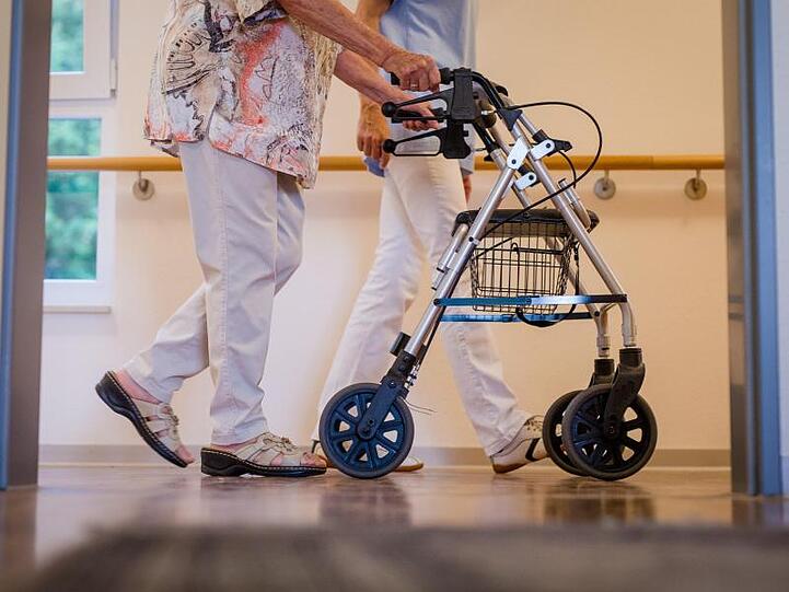 In einem Pflegeheim wird eine Bewohnerin von einer Pflegekraft begleitet.
