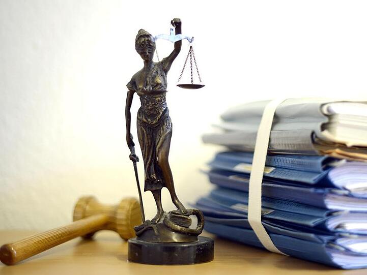 Justitia mit Holzhammer und Aktenstapel. Foto: Volker Hartmann/Archivbild