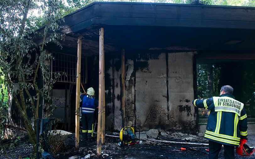 Ein Feuerwehrmann steht vor dem angekohlten Gehege der Affen. Im Straubinger Tiergarten ist ein Feuer ausgebrochen...