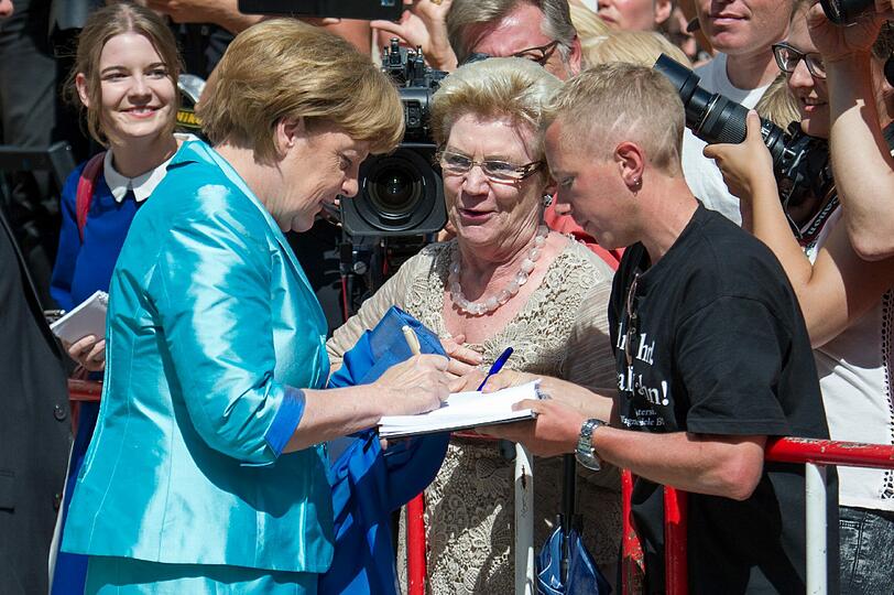 Bundeskanzlerin Angela Merkel gibt Autogramme.