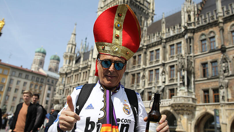 Weißes Trikot, rote Bischofsmütze und in der Hand ein Helles. Weißes Trikot, rote Bischofsmütze und in der Hand ein Helles.