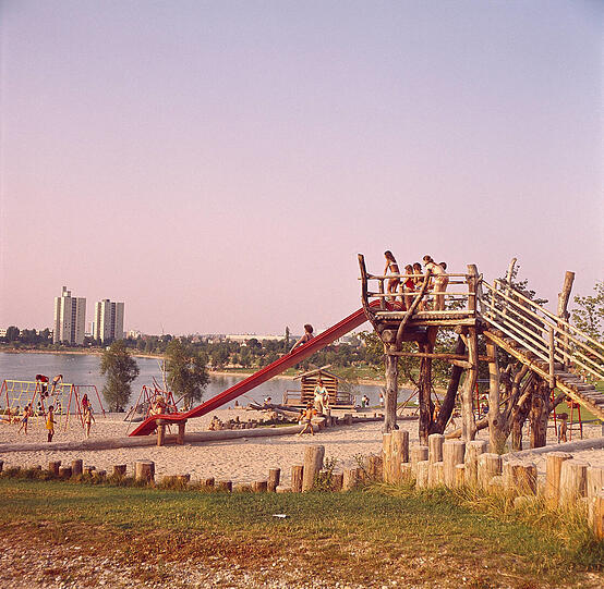 Die Haarpracht, Koteletten, Blümchen-Muster und knallige Farben verraten es: Wir sind mitten in den 70er Jahren - am Spielplatz und auf der Liegewiese am Lerchenauer See.