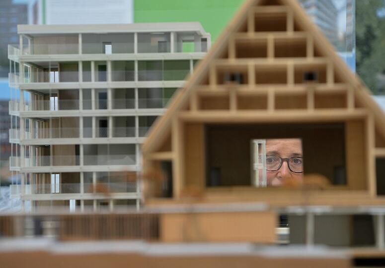 Eine Frau begutachtet im Deutschen Architekturmuseum (DAM) in Frankfurt am Main das Modell des Kultur + Kongress Forums Altötting (vorn) und des Baugruppenprojekts R50 Berlin.