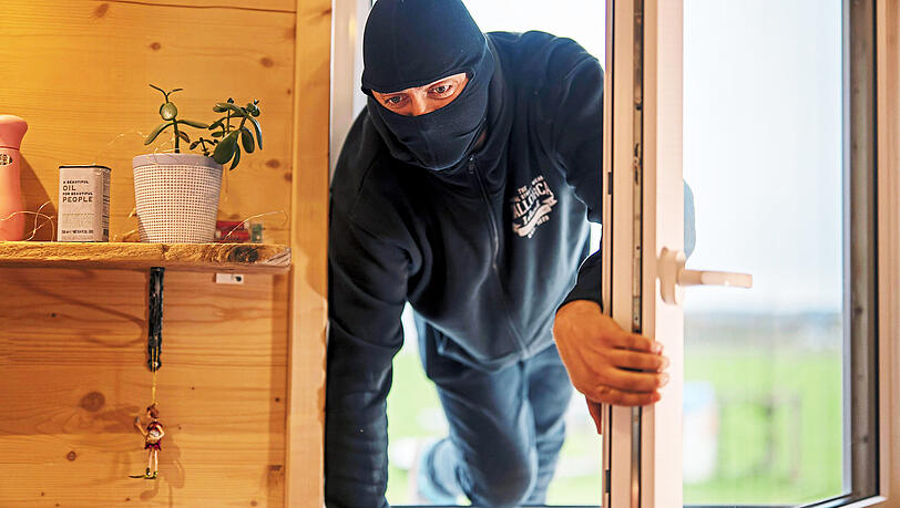Ein Einbrecher steigt durch ein aufgehebeltes Fenster in eine fremde Wohnung ein. Imago
