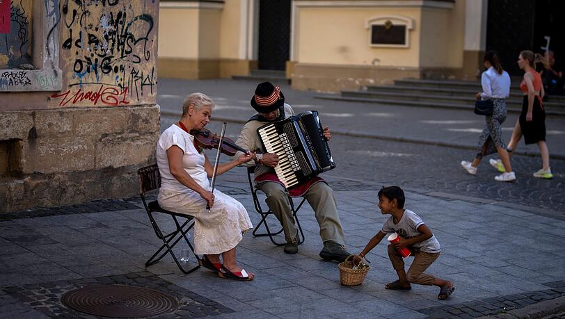 Ein Kind versucht, zwei Straßenmusikern in der Innenstadt von Lwiw Geld zu stehlen. Ein Kind versucht, zwei Straßenmusikern in der Innenstadt von Lwiw Geld zu stehlen.