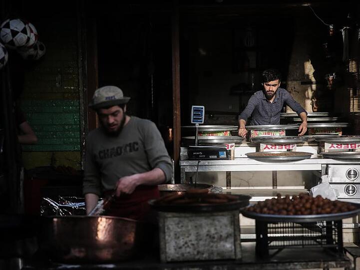 Syrische Verkäufer bereiten auf einem Straßenmarkt traditionelle Süßigkeiten zu.
