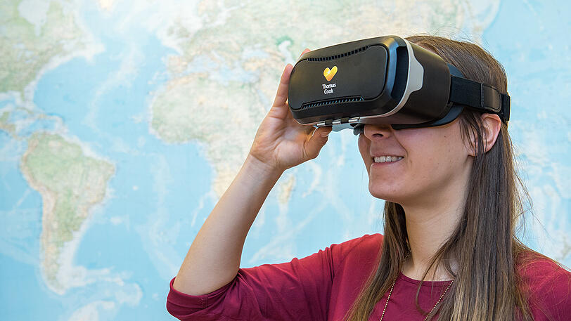 Eine Frau schaut sich mit einer VR-Brille in einem Reisebüro in Hannover potenzielle Reiseziele an.