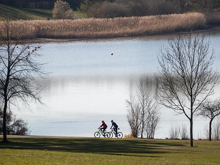 Zwei Fahrradfahrer fahren entlang am Rothsee. Foto: Daniel Karmann/dpa
