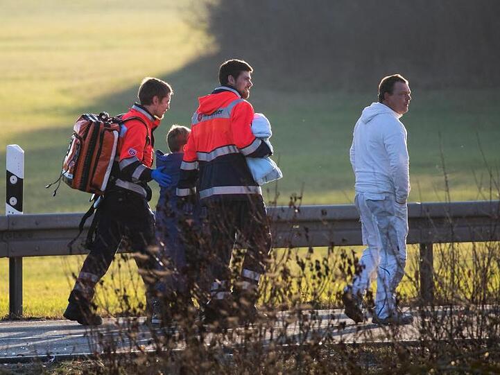 Rettungskräfte kümmern sich nach dem verheerenden Schulbus-Unfall um einen Jungen.